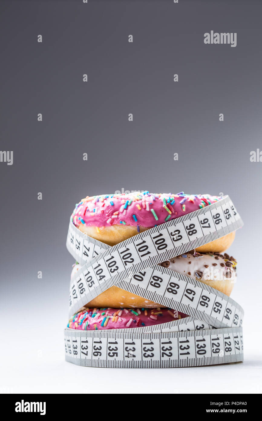 Drei bunte Donuts in einen Schneider Massband umwickelt. Stockfoto