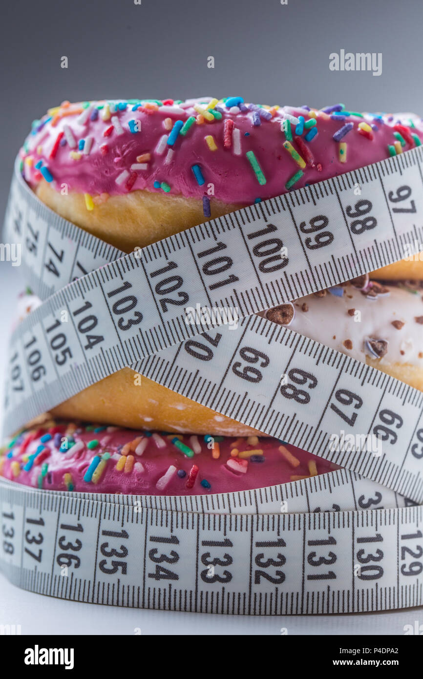 Drei bunte Donuts in einen Schneider Massband umwickelt. Stockfoto