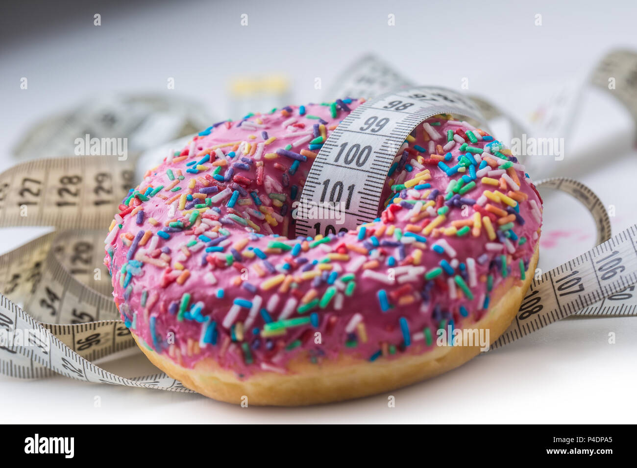 Close-up pink frosted Donut mit weißen Maßband anpassen. Stockfoto