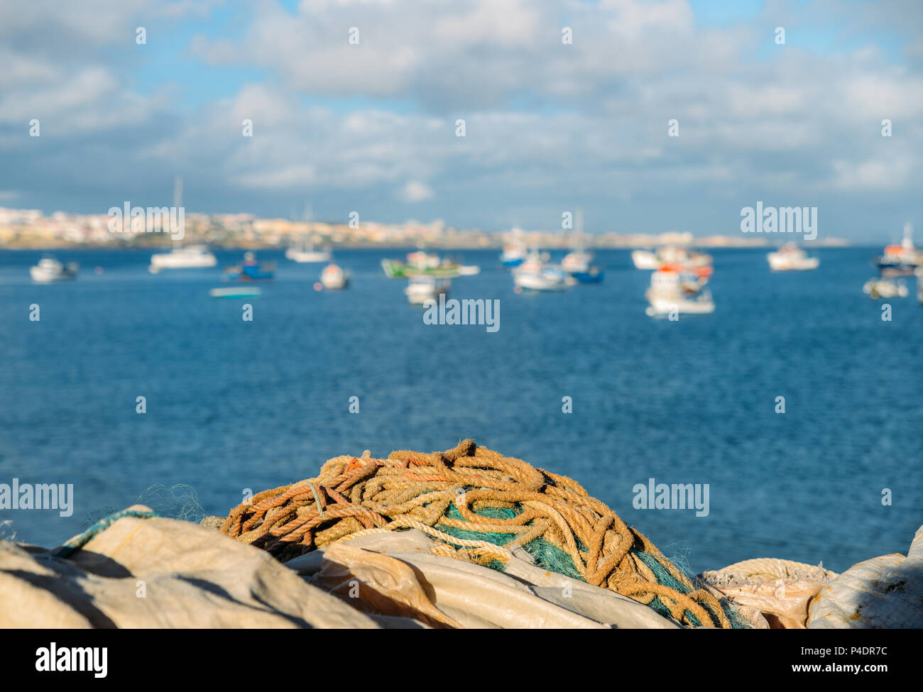 Fischernetze, das Meer und das Dorf Blick auf den Hintergrund, selektiver Fokus - in Cascais, Portugal erfasst Stockfoto