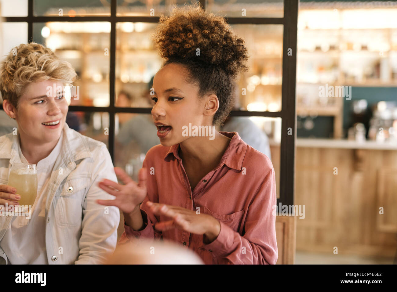 Junge Frau mit Freunden zu reden über Getränke in einem Cafe Stockfoto