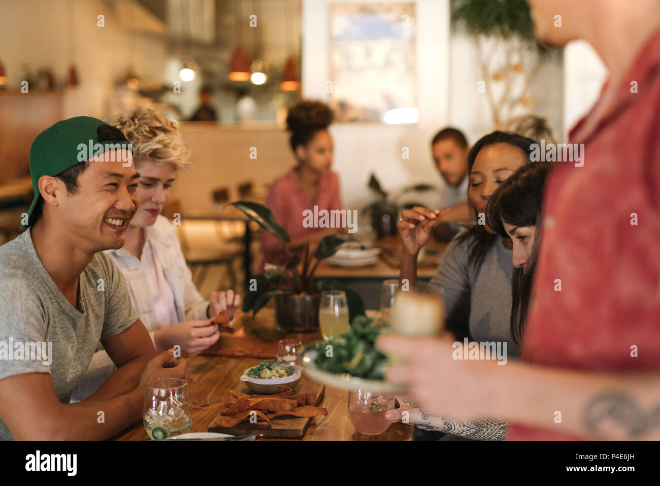 Lächelnden jungen Freunden vergnügen, während in einem Bistro sitzen Stockfoto