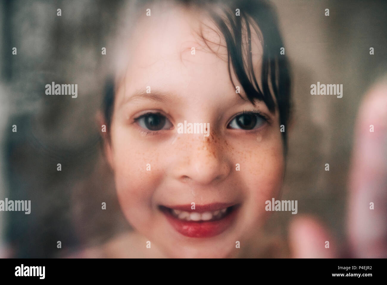 Porträt eines lächelnden Mädchen durch die Feuchten Dusche Glas suchen Stockfoto