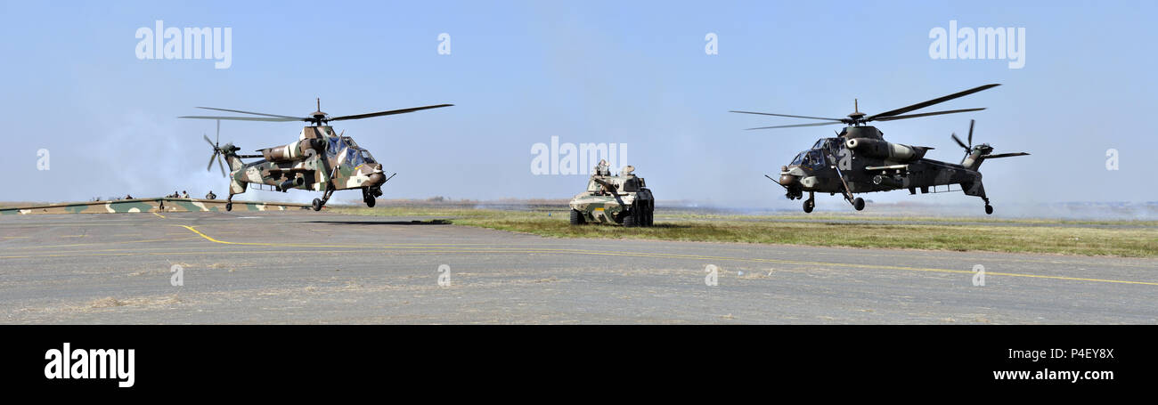 Südafrikanische militärische Hardware. Zwei Hubschrauber und eine Rooikat Rooivalk Artillerie Fahrzeug. Stockfoto
