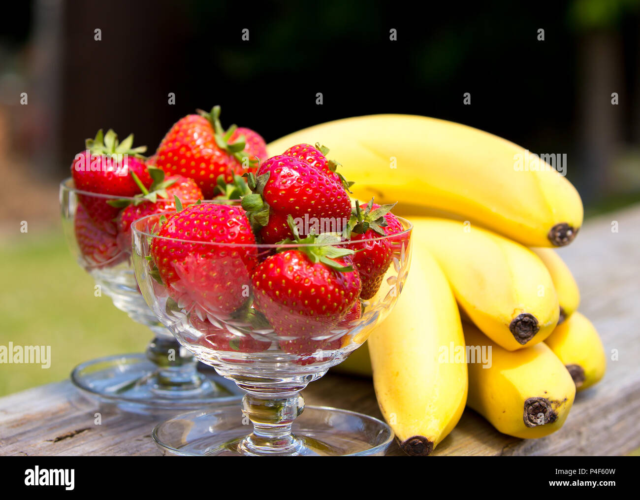 Frische Erdbeeren in Kristallglas Dessertgerichte & Bananen im Freien, sonniger Sommertag. Genießen Sie UK Sommerferien im Garten. Staycation. Stockfoto