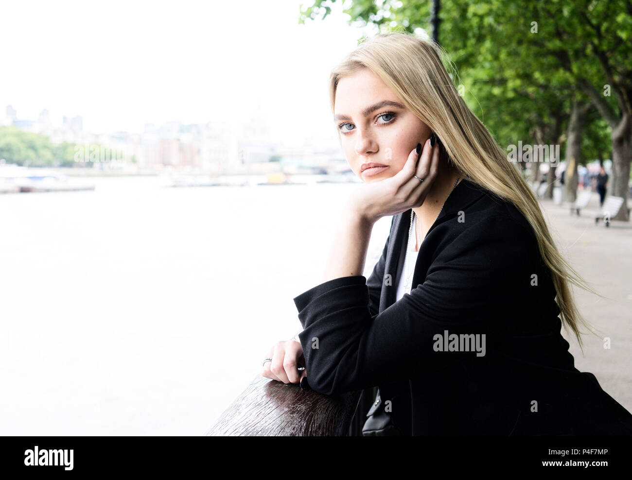 Junges Mädchen in London von dem Fluss in einem Anzug für ein Foto posiert Stockfoto