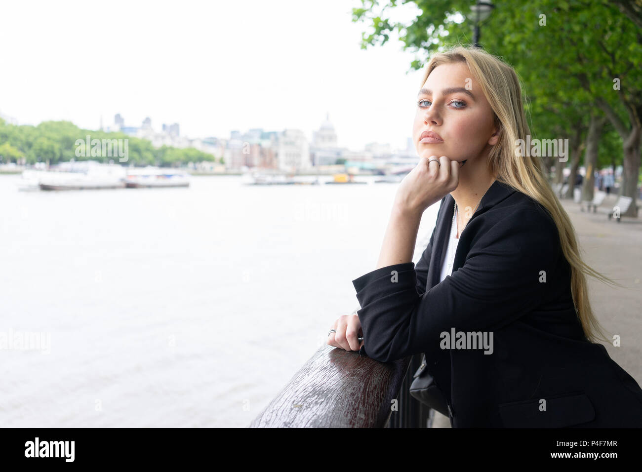 Junges Mädchen in London von dem Fluss in einem Anzug für ein Foto posiert Stockfoto