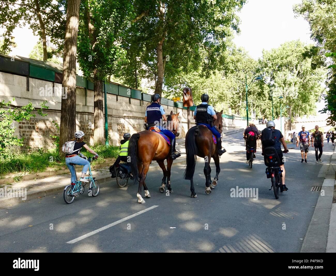 Kinder und Erwachsene Reiten Fahrräder letzten zwei gendarmen auf dem Pferderücken patrouillieren die richtige Bank Rives de Seine, während der Fête de la musique, Paris, Frankreich Stockfoto