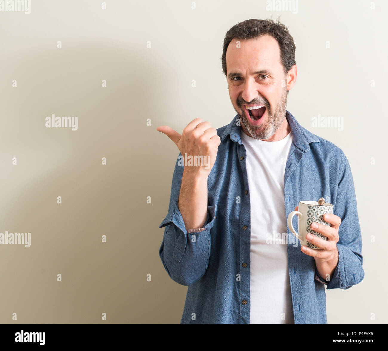 Ältere Menschen trinken Kaffee in einem Becher zeigt mit Finger- und oben mit glücklichen Gesicht lächelnd Stockfoto