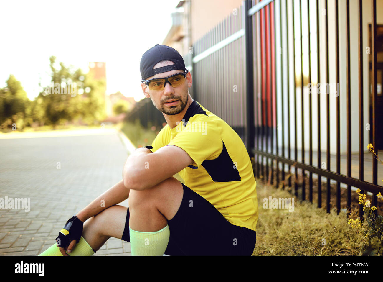 Ein Mann in Sportkleidung sitzt auf der Straße. Stockfoto