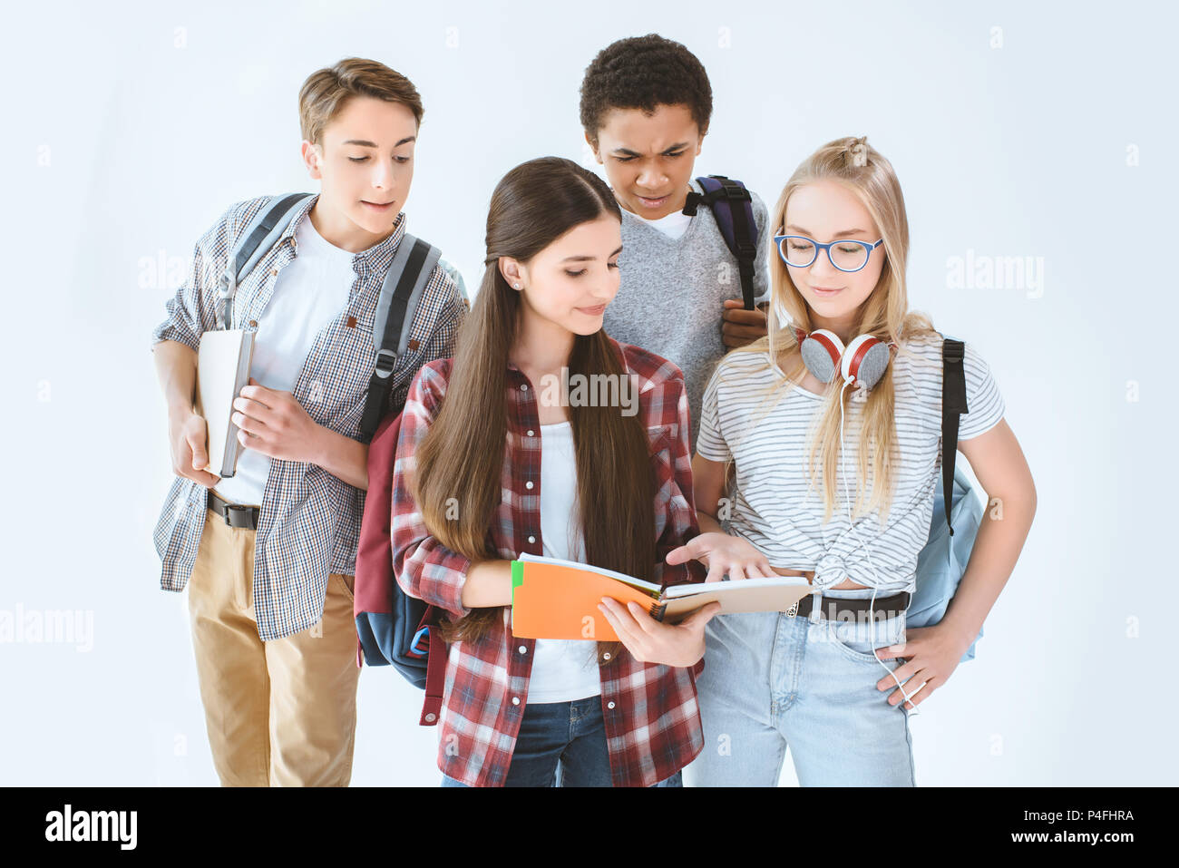 Jugendmädchen diskutieren, Hausaufgaben, während multikulturelle jungen Blick von hinten auf Weiß isoliert Stockfoto