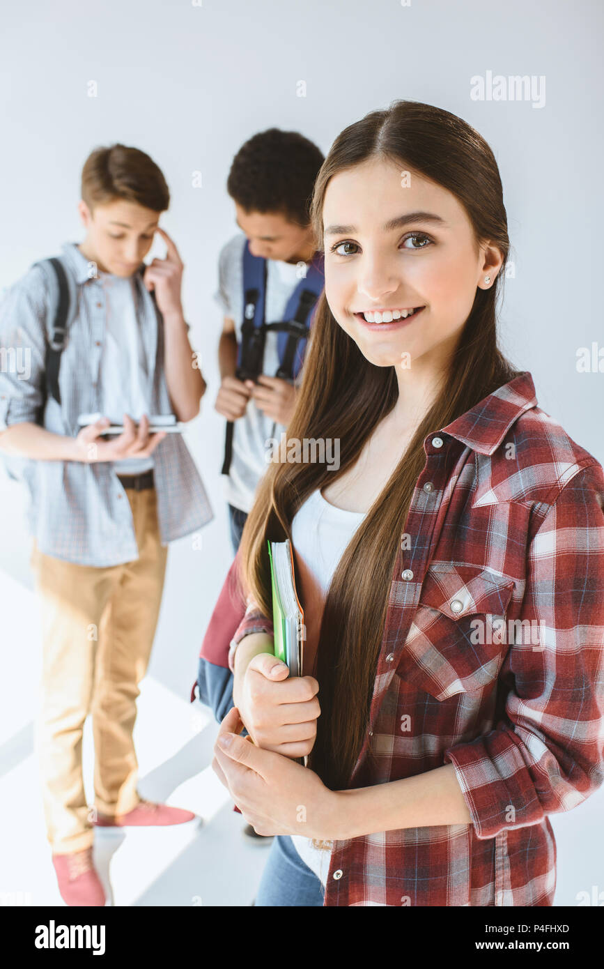 Portrait von lächelnden Teenager mit Notebook, Kamera, Suchen mit Multiethnischen Jungen hinter auf Weiß isoliert Stockfoto