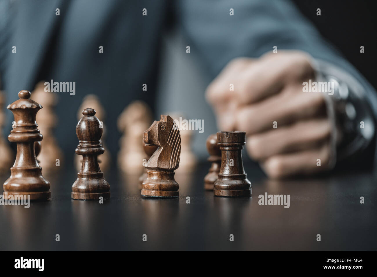 Selektiver Fokus der Holz- Schachfiguren auf Tisch und Geschäftsmann hinter sitzen Stockfoto