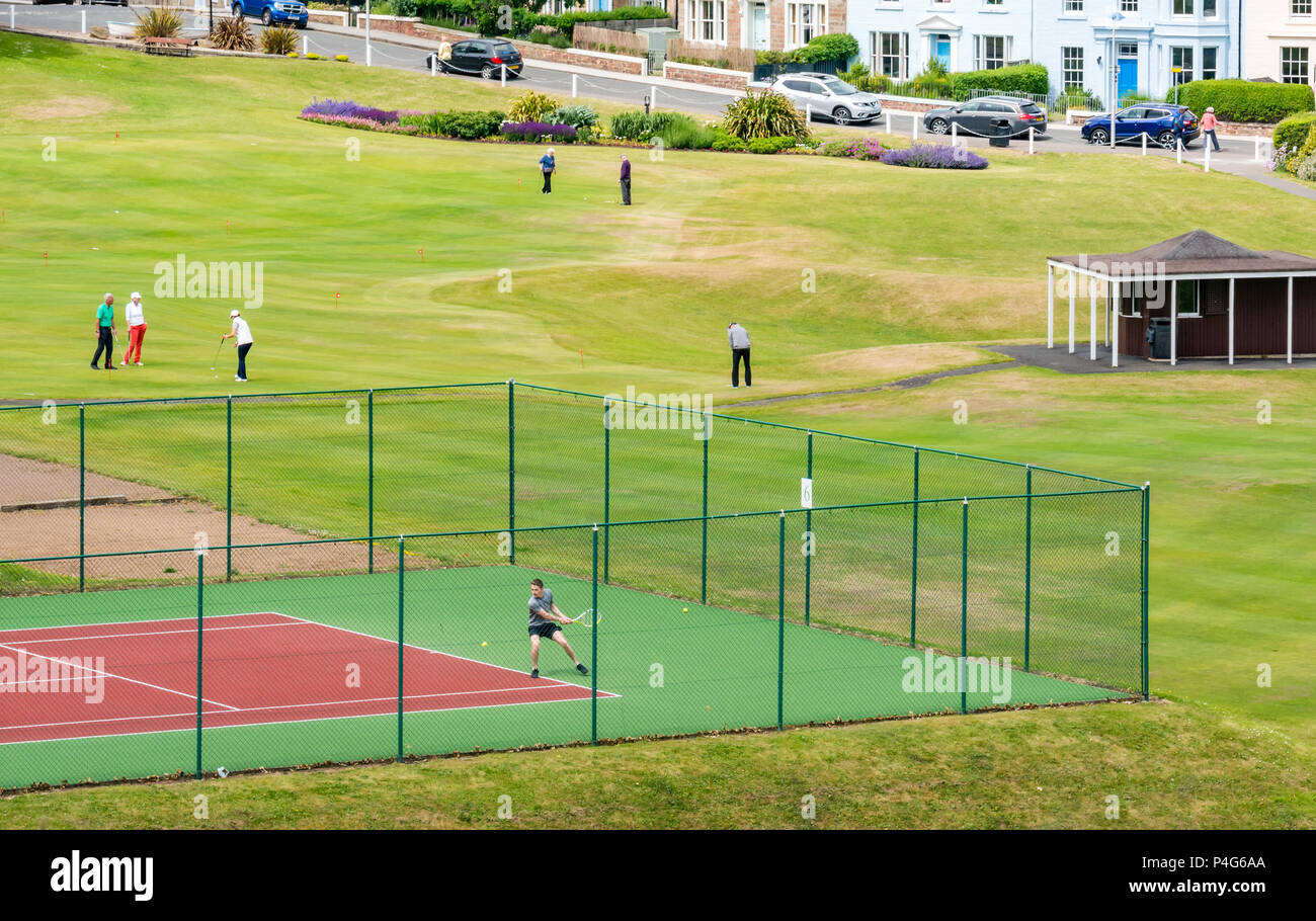 North Berwick, Schottland, Vereinigtes Königreich, 22. Juni 2018. Ein paar genießen Sie eine Partie Tennis und Menschen auf dem Putting Green an einem sonnigen Tag im Sommer. North Berwick ist die Heimat von mehreren Putting Greens und Golfplätze. Stockfoto