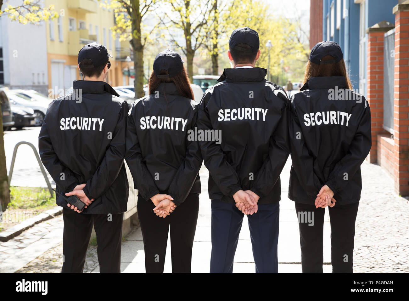 Ansicht der Rückseite des Security Guards mit den Händen hinter dem Rücken in einer Reihe Stockfoto