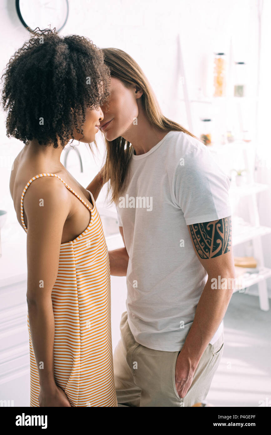 Junger Mann mit tätowierten Hand küssen afrikanische amerikanische Freundin Stockfoto