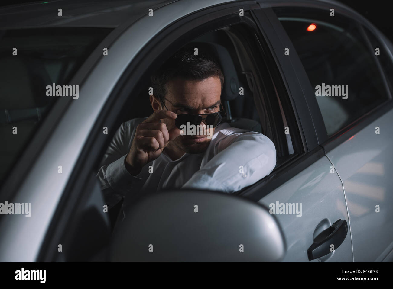 Schwere männliche Undercover Agent, der Überwachung von Auto Stockfoto