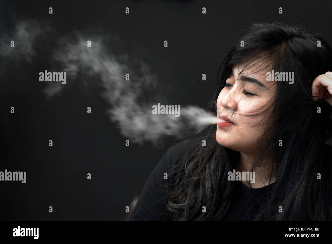 Eine Frau für ein Foto posieren, während vaping während eine elektronische Zigarette Messe in Jakarta, Indonesien. Stockfoto