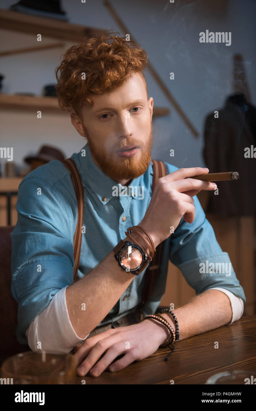 Stilvolle Junge Mann rauchen Zigarre an Kleidung Design Studio Stockfoto