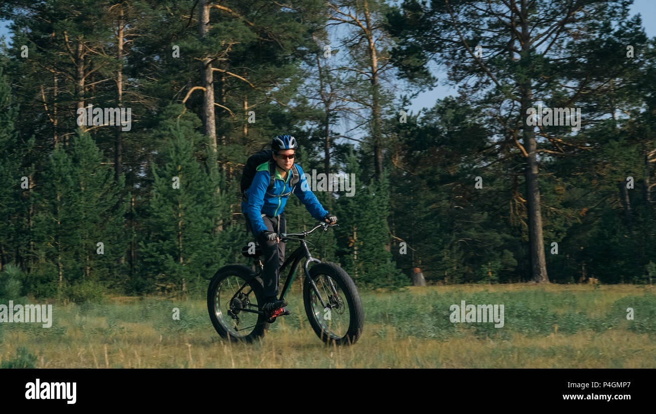 Fat bike auch fatbike oder Fat Tire Bike im Sommer Reiten im Wald. Der Kerl fährt Fahrrad zwischen Bäumen und Stümpfe. Er überwindet einige obstac Stockfoto