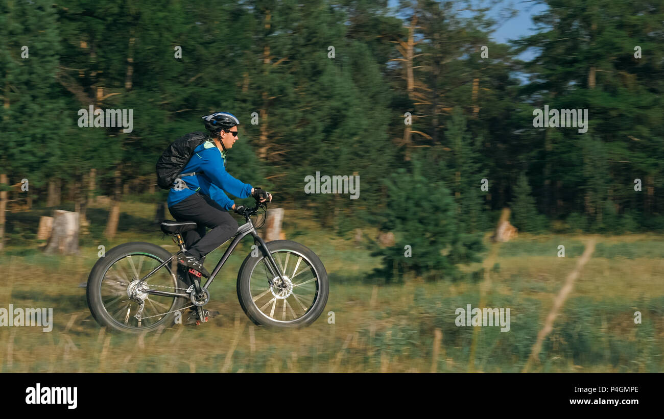 Fat bike auch fatbike oder Fat Tire Bike im Sommer Reiten im Wald. Der Kerl fährt Fahrrad zwischen Bäumen und Stümpfe. Er überwindet einige obstac Stockfoto