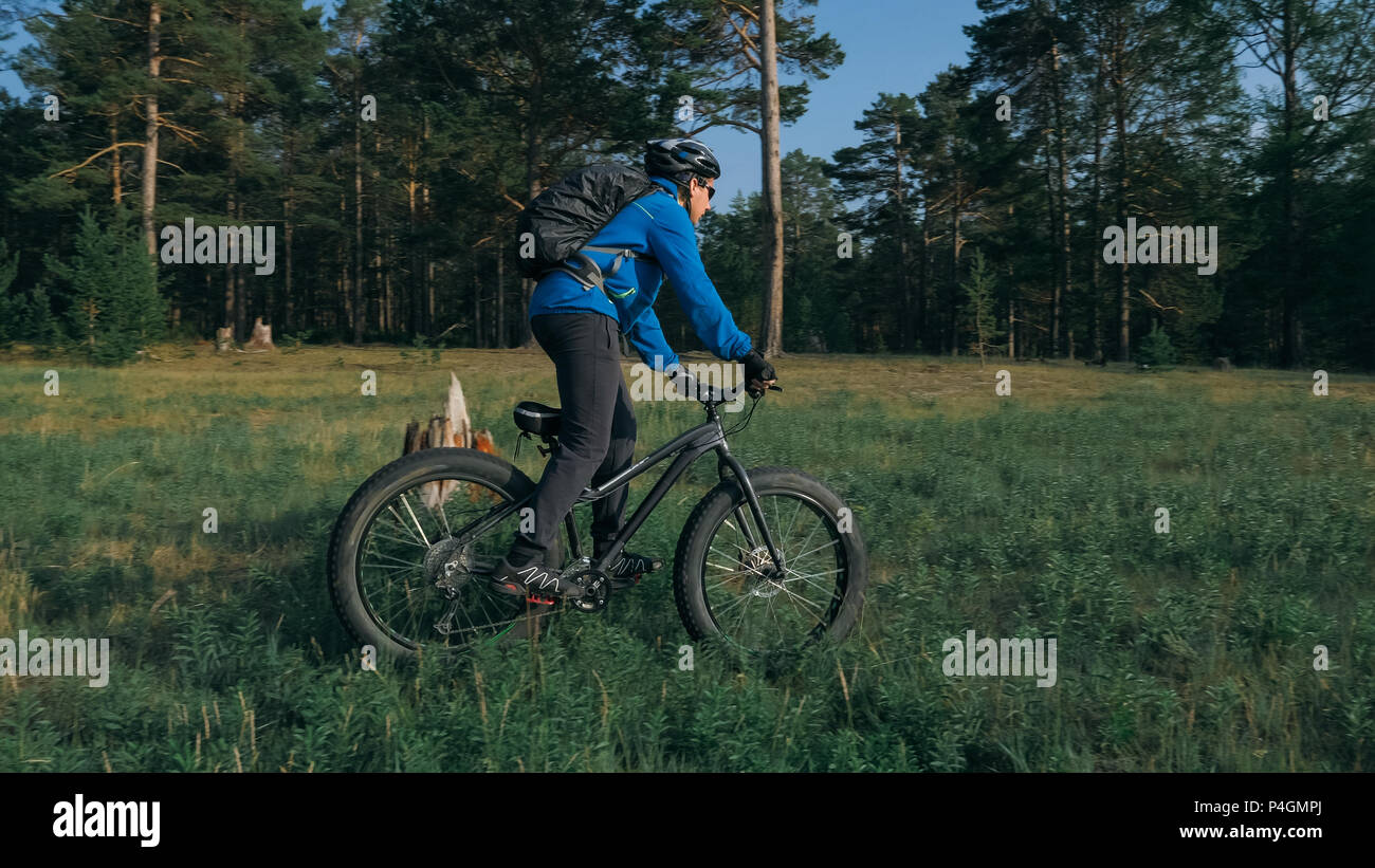 Fat bike auch fatbike oder Fat Tire Bike im Sommer Reiten im Wald. Der Kerl fährt Fahrrad zwischen Bäumen und Stümpfe. Er überwindet einige obstac Stockfoto