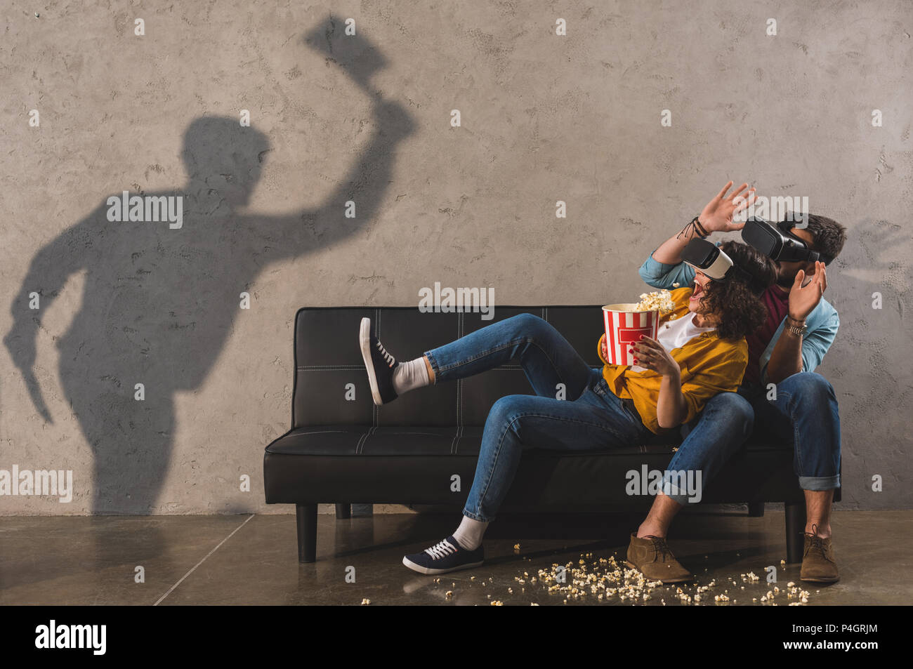 Schatten der Mann mit Axt und Angst Paar mit Popcorn mit Virtual reality Headset Stockfoto