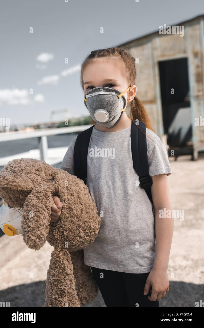 Kind in Schutzmaske holding Teddybär auf Brücke, Luftverschmutzung Konzept Stockfoto