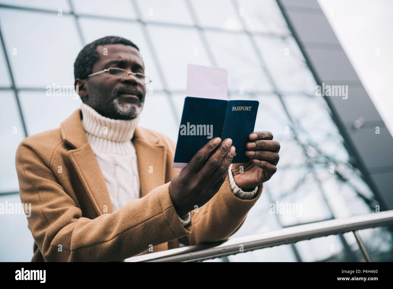 Im mittleren Alter afrikanische amerikanische Mann stand mit einem Pass und Kontrolle der Abreise im Ticket Stockfoto