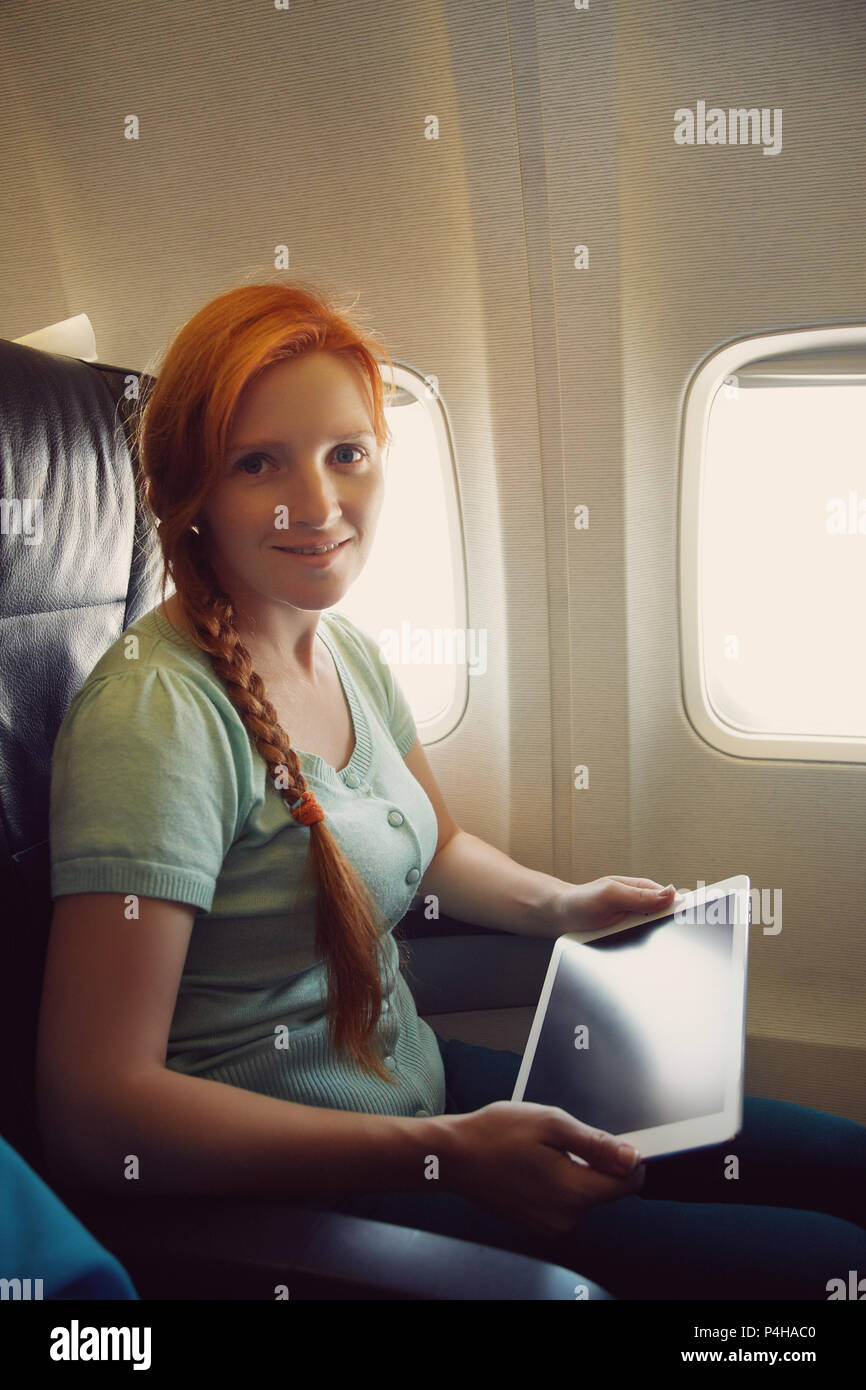 Frau in einen Stuhl, an Bord der Flugzeuge. Mädchen mit Tablet-PC in einem Flugzeug. Flug und Reisen Stockfoto