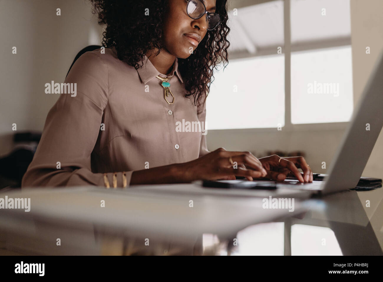Geschäftsfrau am Laptop von zu Hause aus arbeiten. Frau Unternehmer zu Hause sitzen Arbeiten am Laptop mit Geschäftsdokumenten auf dem Tisch. Stockfoto