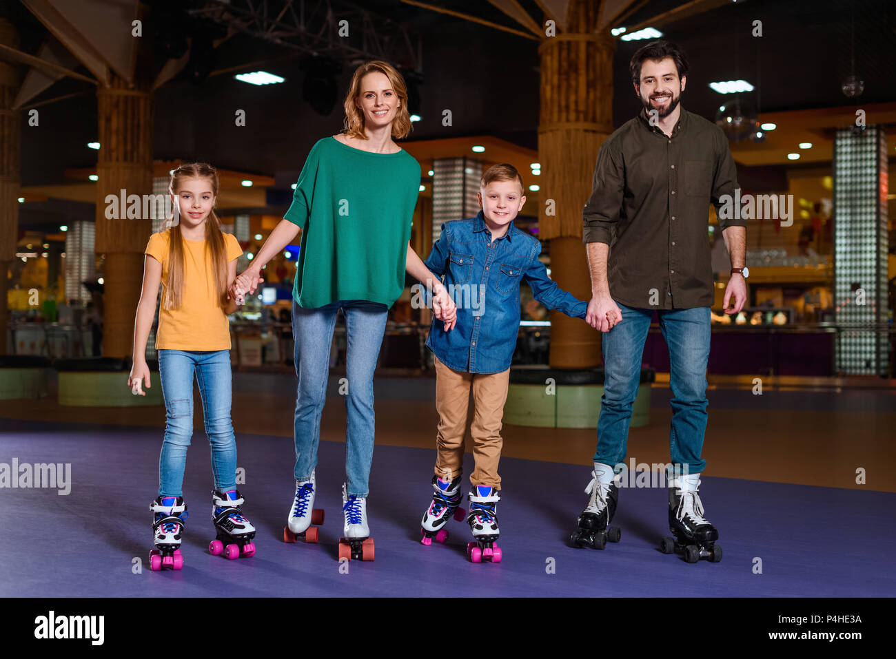 Eltern und Kinder gemeinsam Schlittschuhlaufen auf Roller Rink Stockfoto