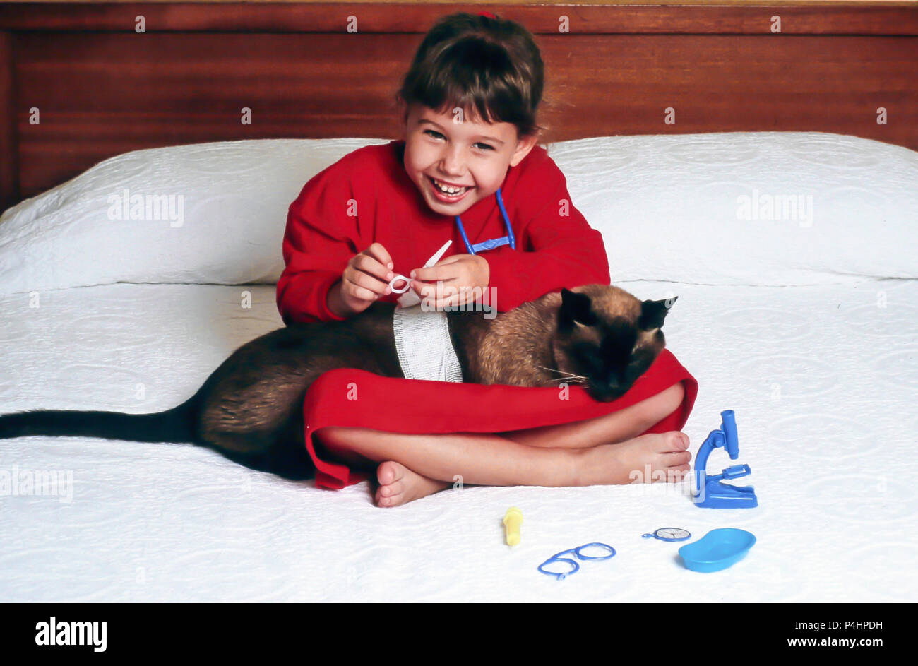 Vintage Bild von kleinen Mädchen spielen Tierarzt mit Ihr Pat Cat, USA Stockfoto