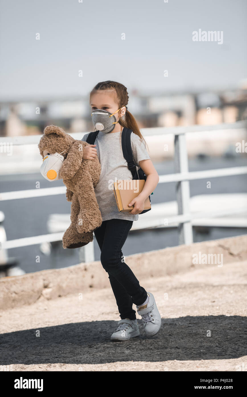 Kind in Schutzmaske holding Teddy und Buch auf Brücke, Luftverschmutzung Konzept Stockfoto