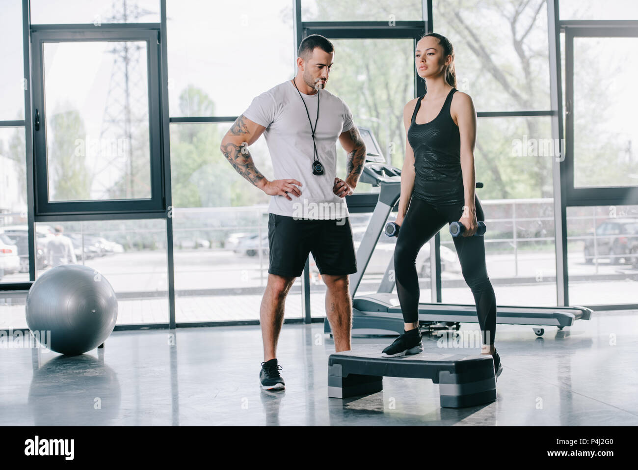 Männliche personal trainer und junge Sportlerin, Step Aerobic Übung mit Hanteln im Fitnessstudio Stockfoto