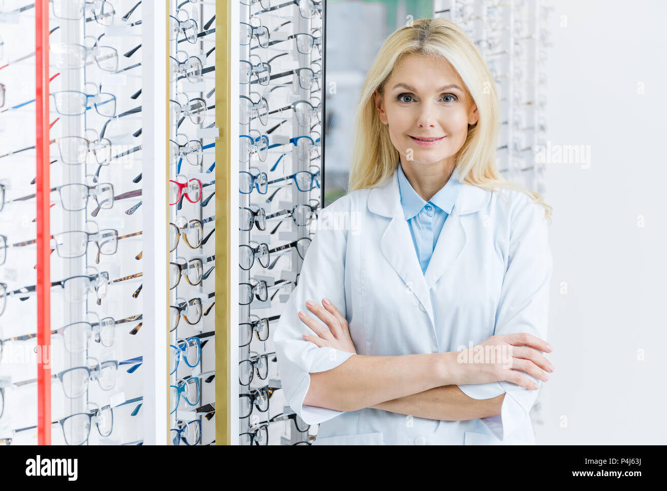Blonde weibliche Augenarzt in Optik mit Brille auf Regalen Stockfoto