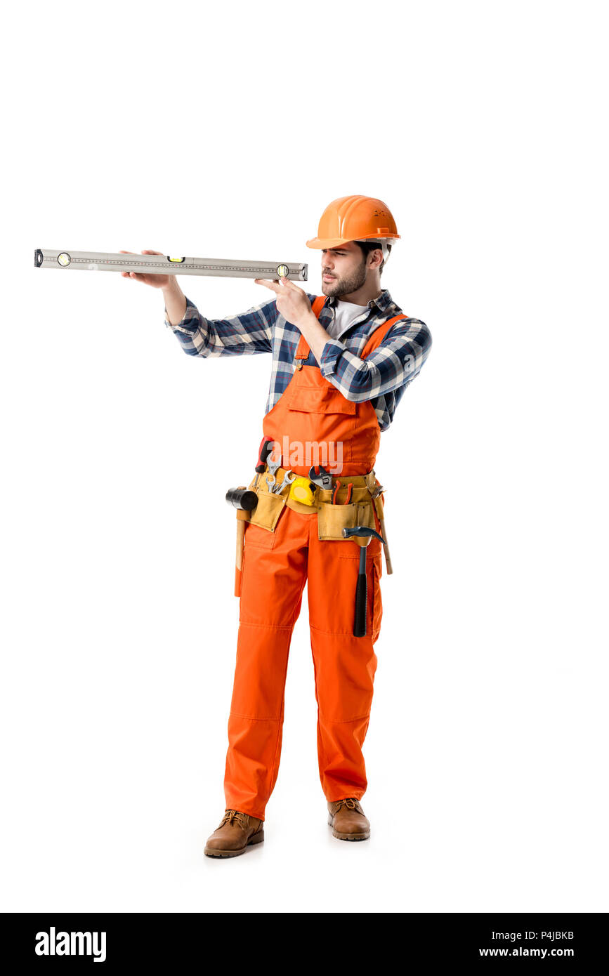 Handwerker in orange Overall und Helm Kontrolle Wasserwaage isoliert auf weißem Stockfoto