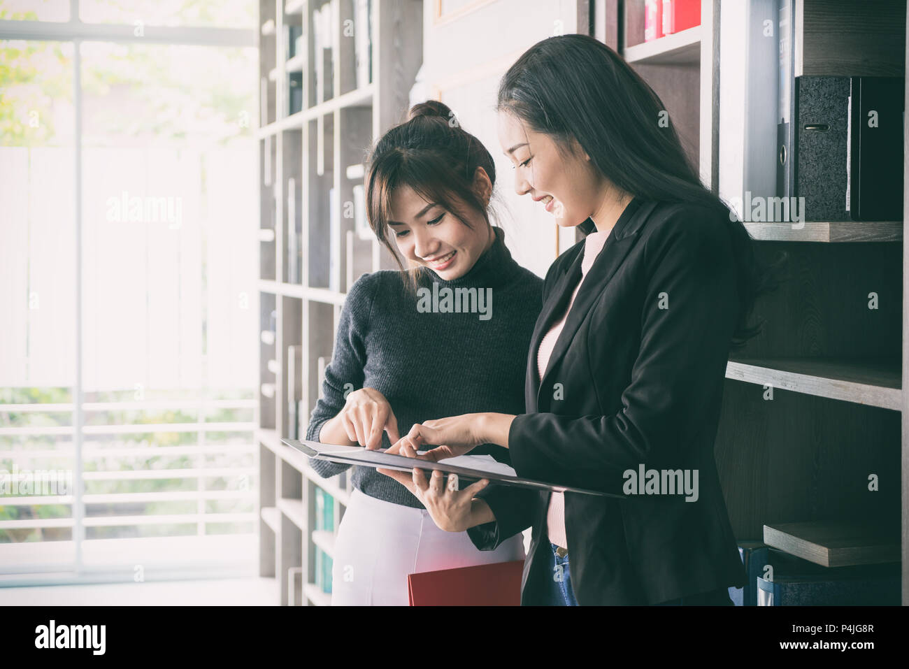Zwei asiatische Geschäftsfrau Kollegen nebeneinander stehen in einem Büro. Sie geschäftsfrau sprechen über Bericht in Dateien. Stockfoto