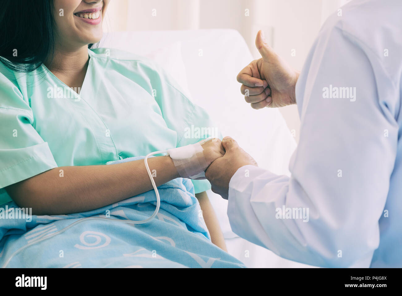 Hand des Menschen Arzt beruhigt seine Patientin mit thump oben im Bett im Krankenhaus. Medizinische Ethik und Vertrauen Konzept. Stockfoto