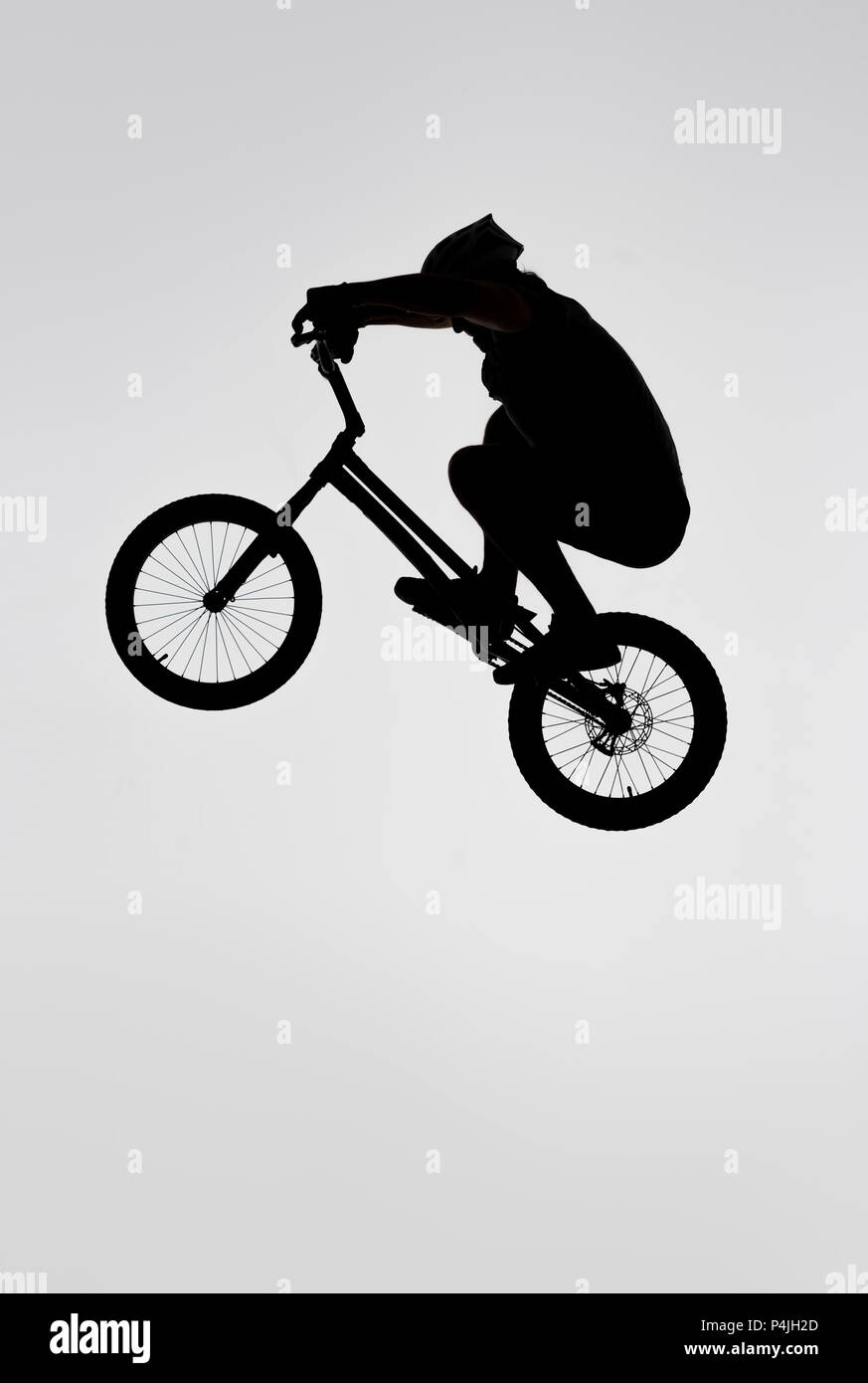 Silhouette des Versuches Radfahrer springen auf dem Fahrrad auf Weiß Stockfoto