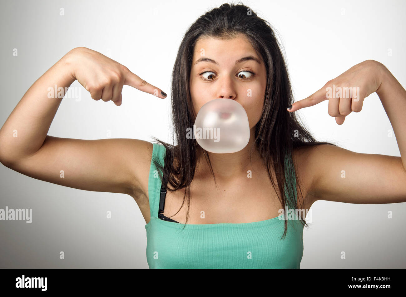 Hübsche junge Mädchen mit gekreuzten Augen Blasen einer großen Kaugummi bubble Stockfoto