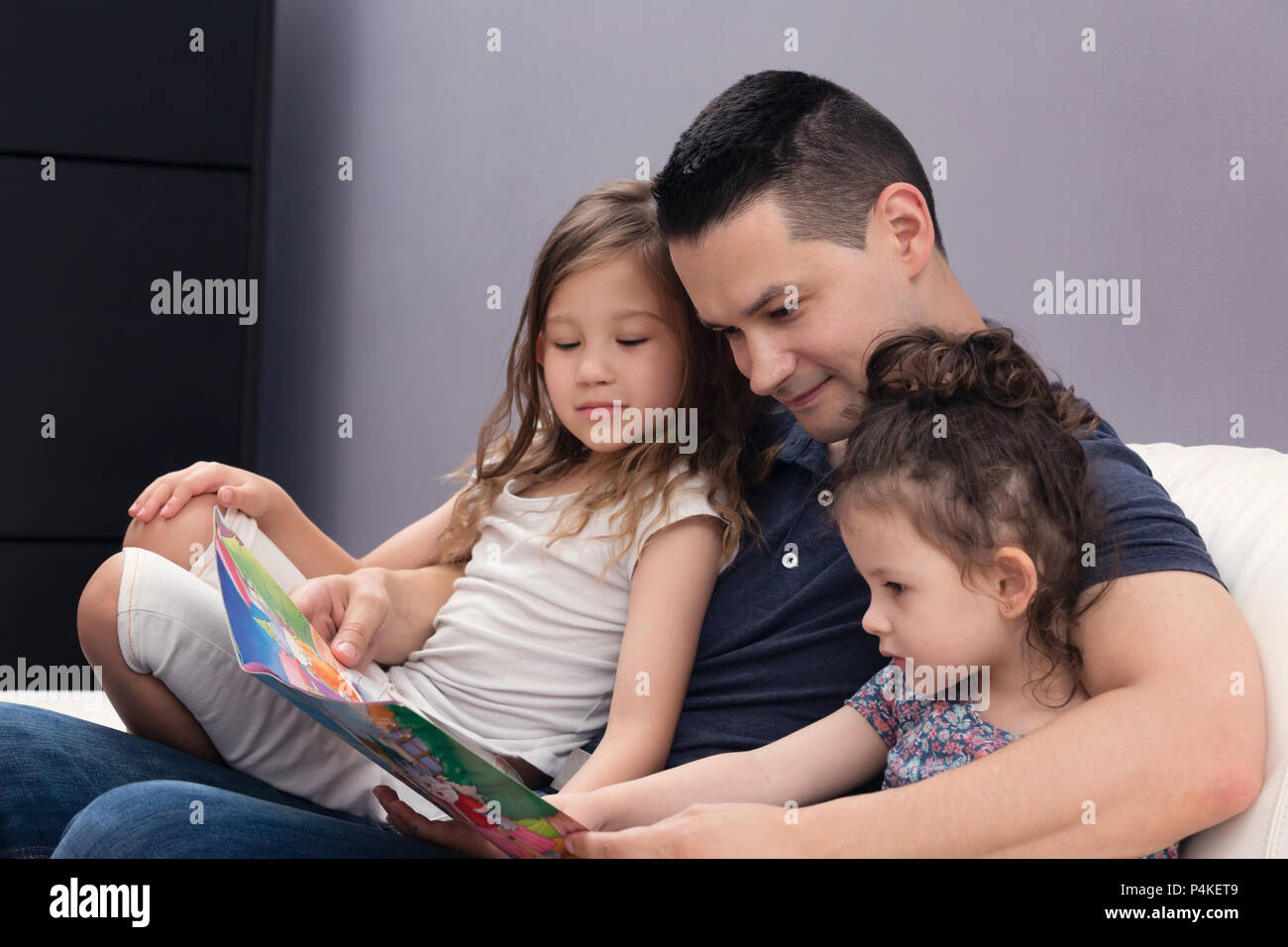 Papa Lesen seiner zwei kleinen Mädchen die Geschichten Stockfoto