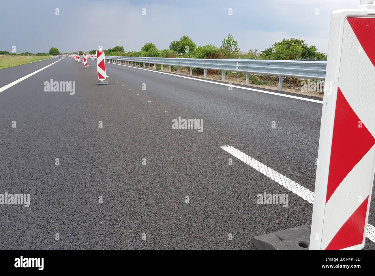 Neue asphaltierte Fahrspur einer Autobahn durch ein viele Straßenarbeiten Marken Zeichen unterteilt. Stockfoto
