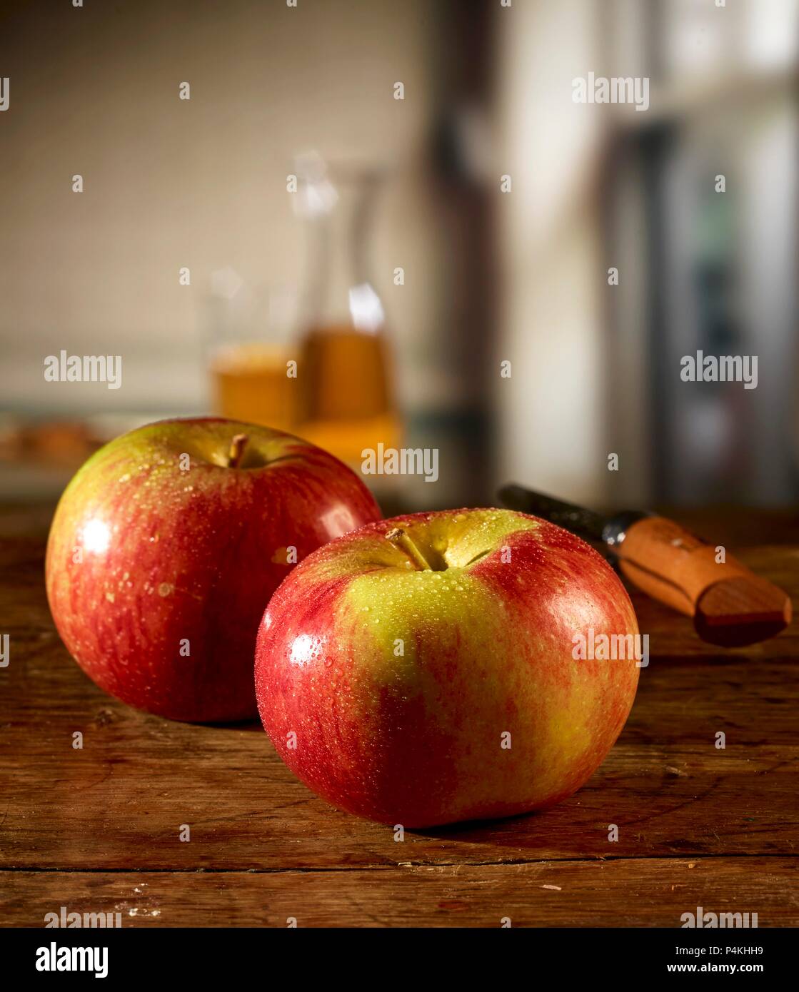 Rote Äpfel auf einem Holztisch und Apfelsaft im Hintergrund Stockfoto