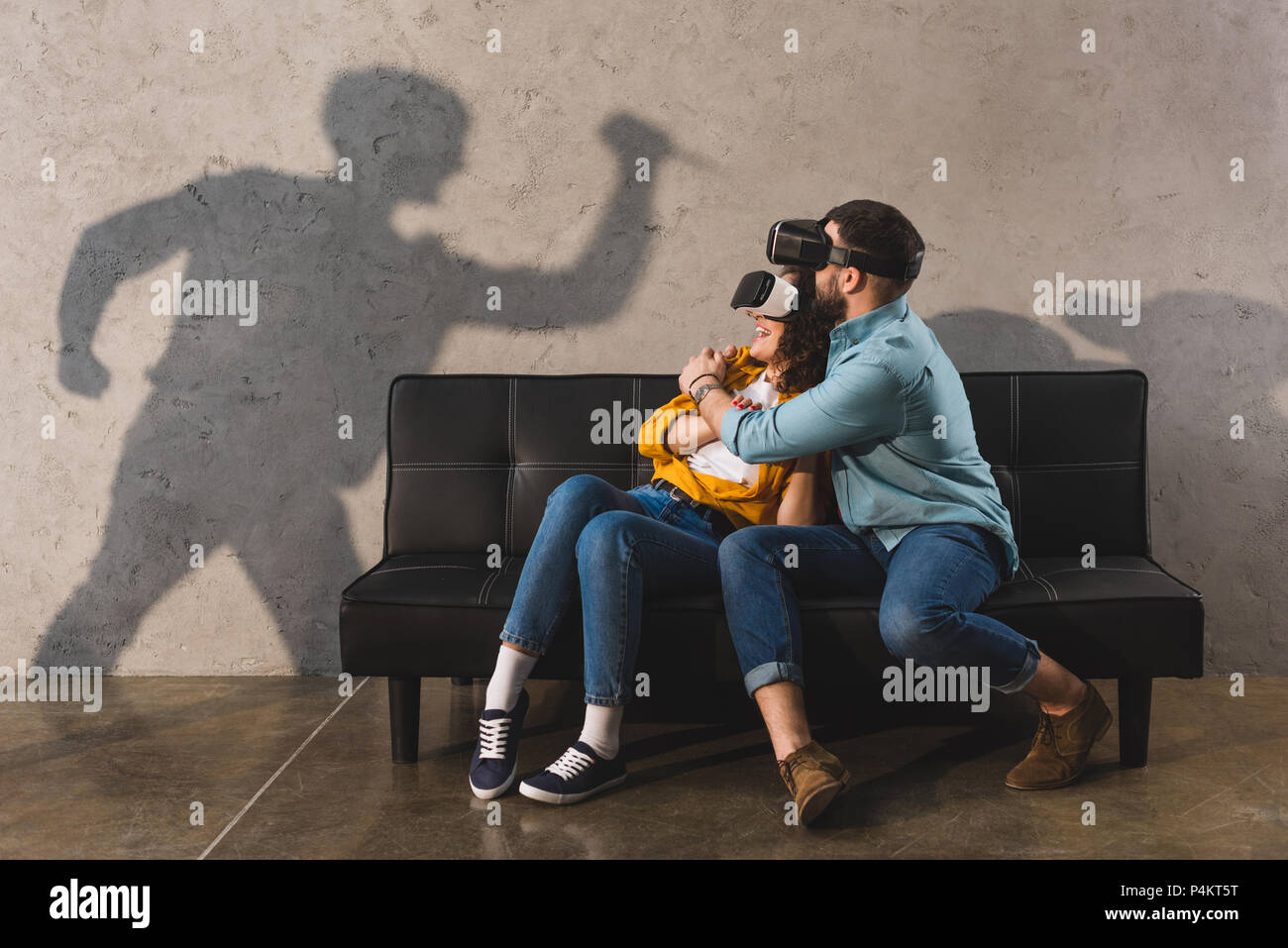 Schatten der Mann mit Messer und erschrocken Paar in virtual reality Headset auf der Couch Stockfoto
