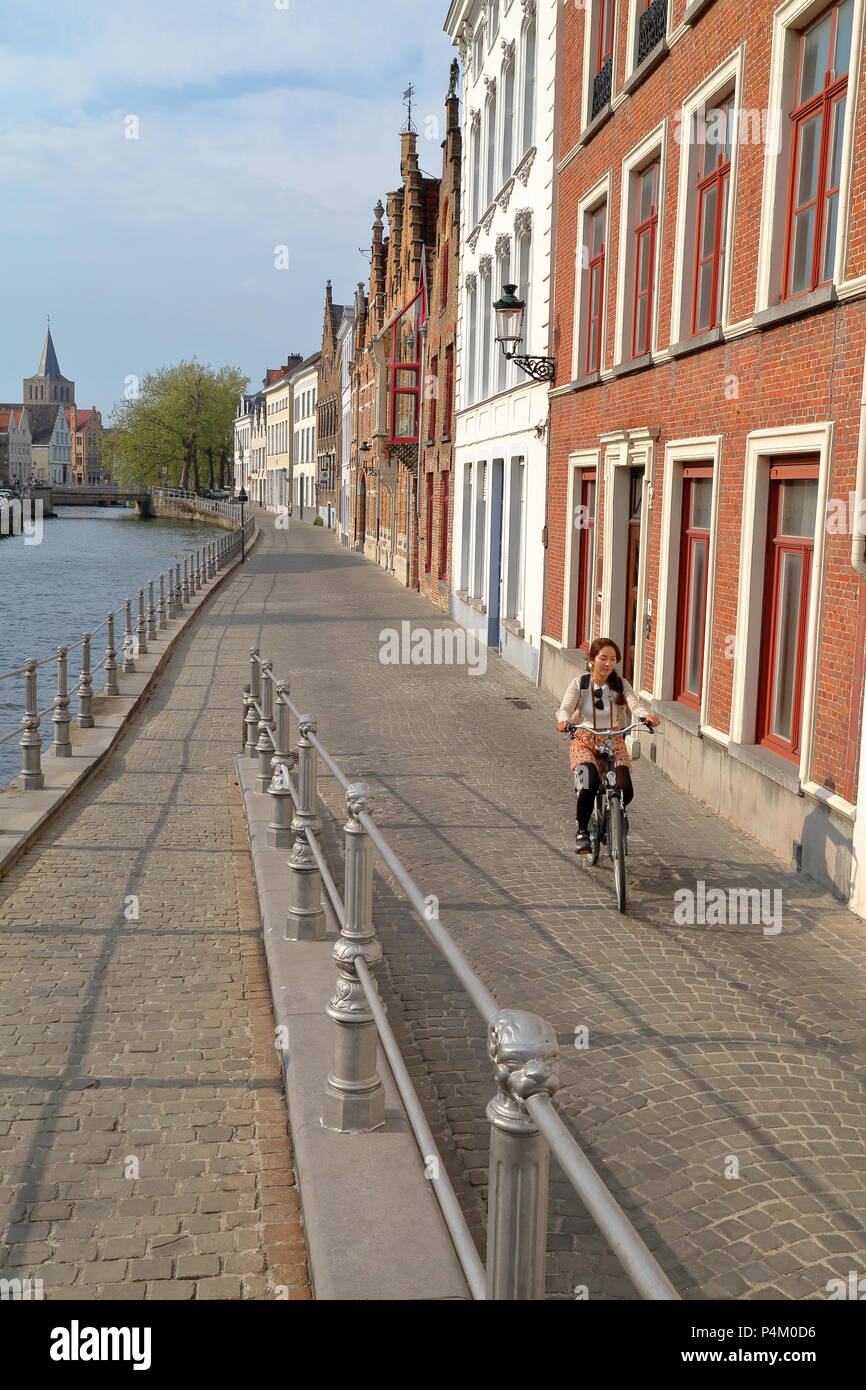 Brügge, Belgien - 20 April 2014: eine junge Frau mit dem Fahrrad entlang Langerei Kanal und traditionellen Fassaden Stockfoto