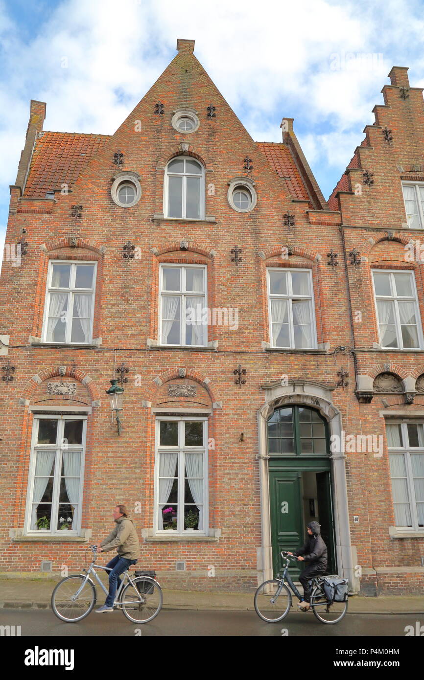 Brügge, Belgien - 18 April 2014: Radfahrer reiten entlang der traditionellen Fassaden Stockfoto