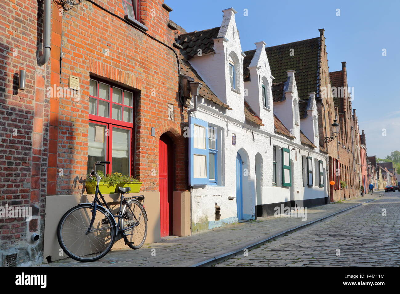 Traditionelles Haus Fassaden entlang eines gepflasterten Straße mit einem Fahrrad im Vordergrund, Brügge, Belgien Stockfoto