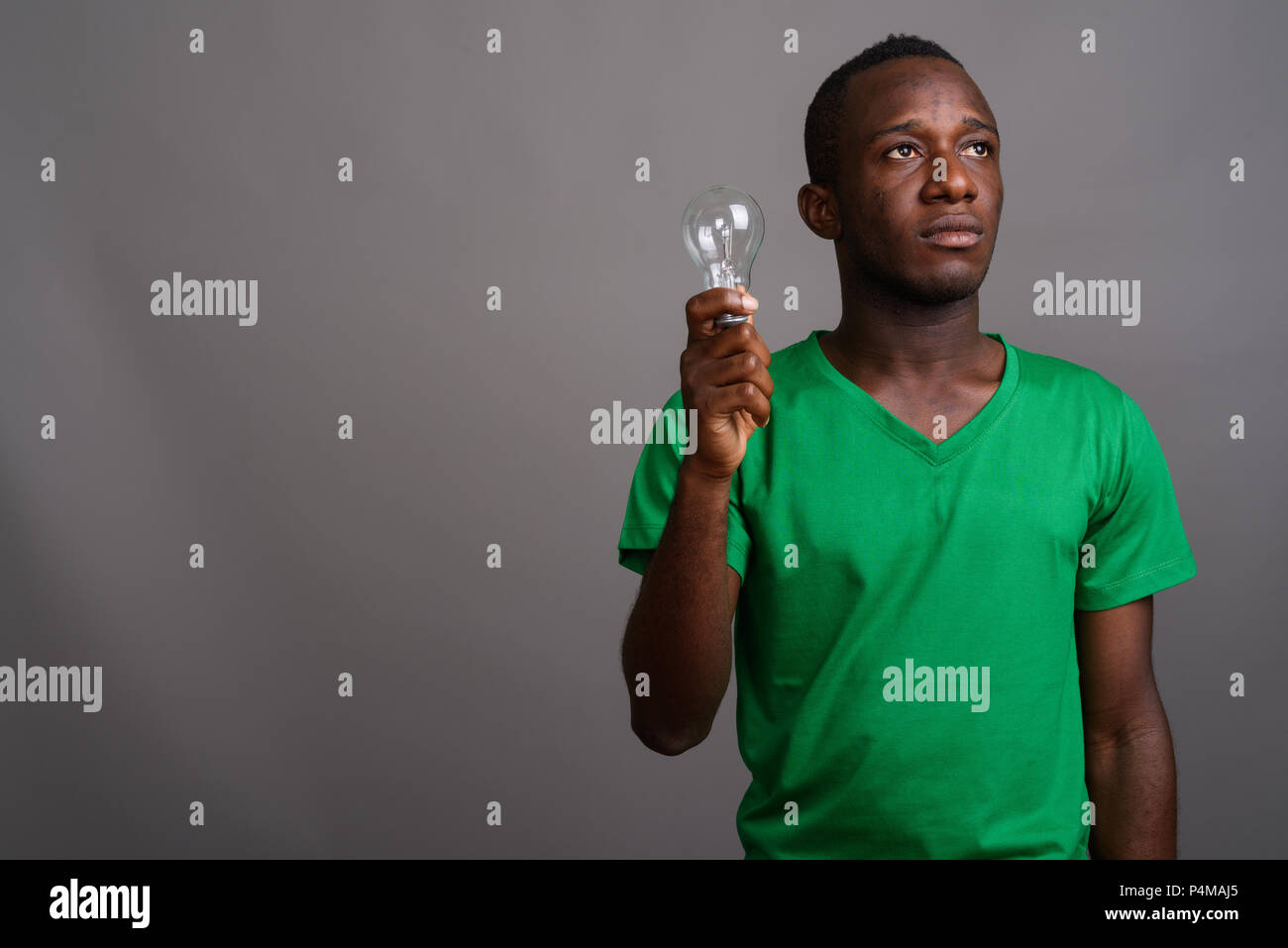 Junge afrikanische Mann, grünes T-Shirt gegen grauer Hintergrund Stockfoto