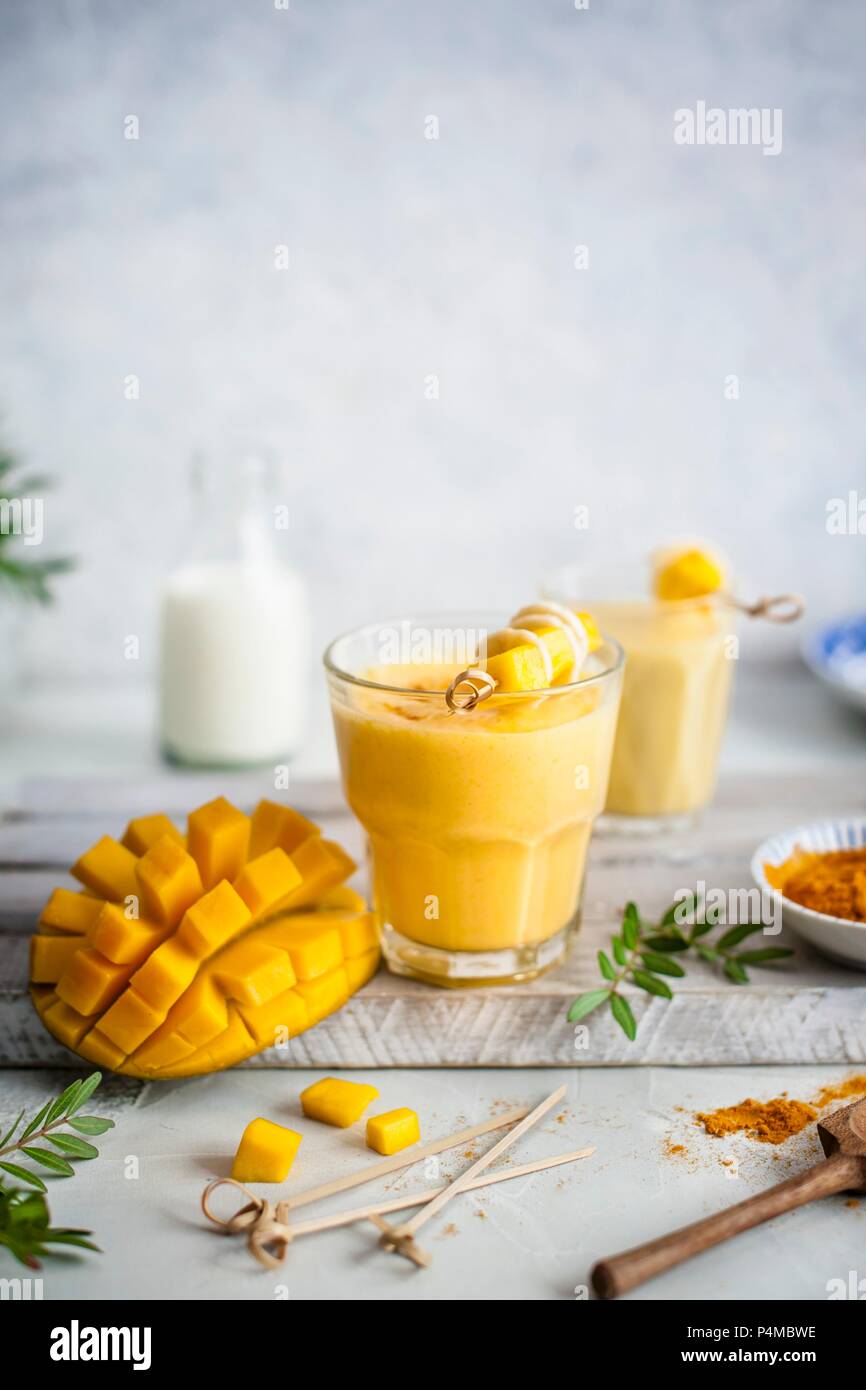 Mango Lassi mit Gelbwurz und Honig, frische Mango auf einer Seite Stockfoto